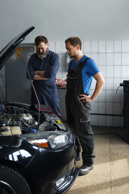 male-mechanics-working-together-car-shop